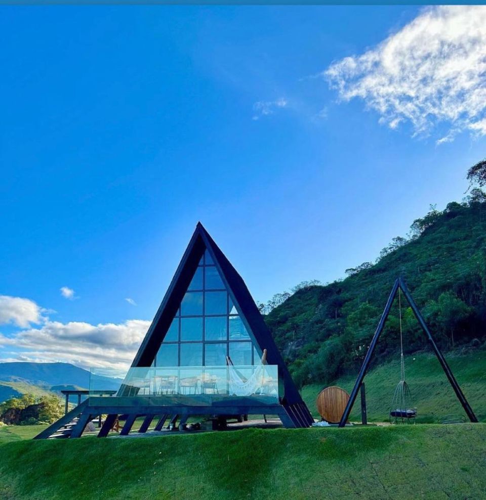 Chalé Diamond em formato A-frame com sauna barril e balanço, cercado por montanhas verdes