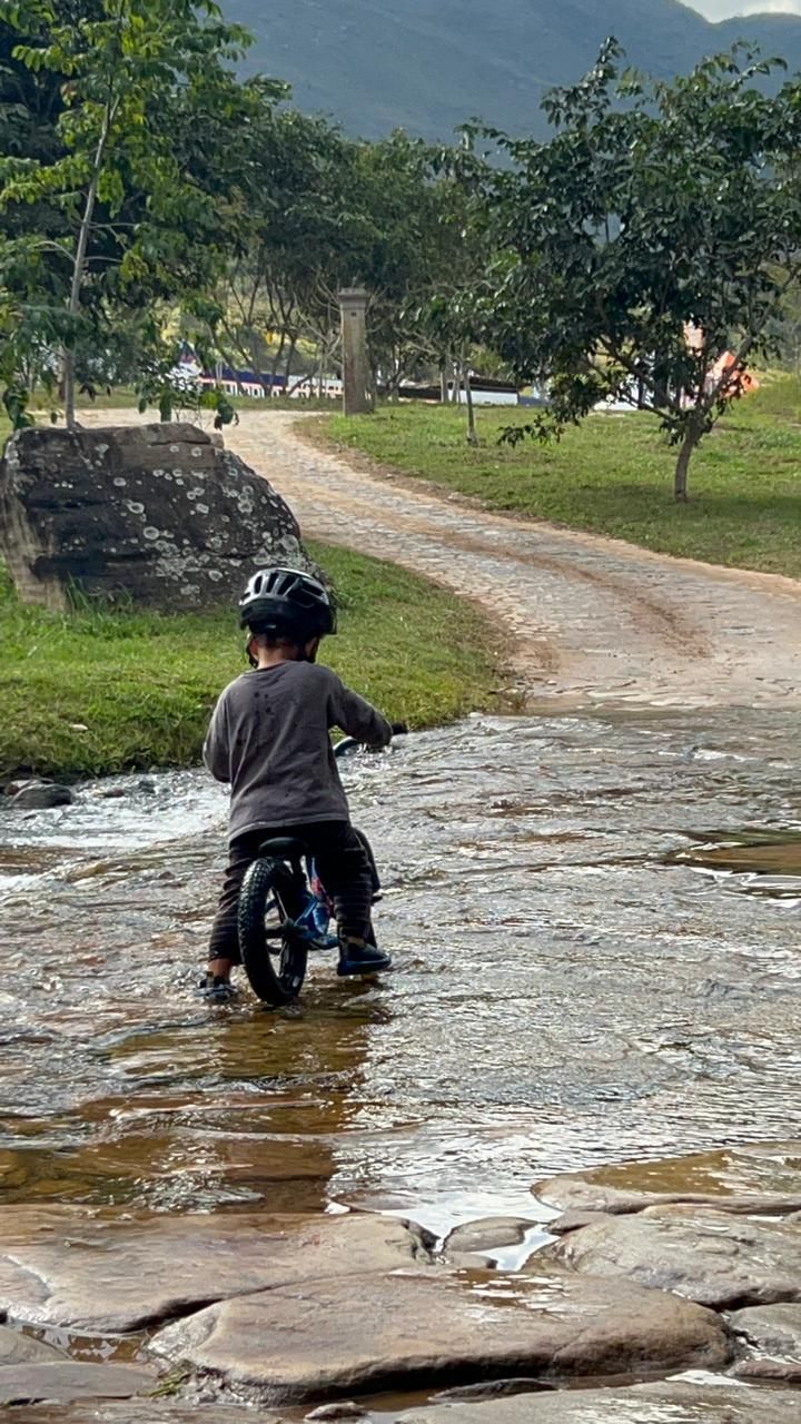 Criança de bicicleta atravessando um riacho de água limpa no haras