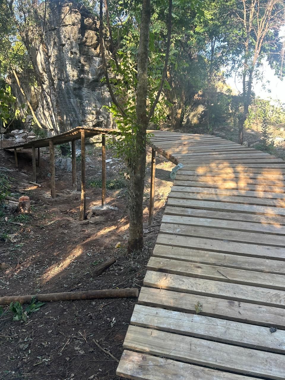 Passarela de madeira construída ao lado de um paredão de escalada