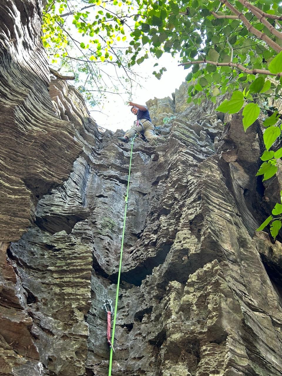 Escalador em paredão de rocha natural cercado por vegetação verde