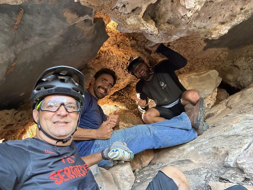 Grupo de amigos dentro de uma gruta de pedra durante uma trilha