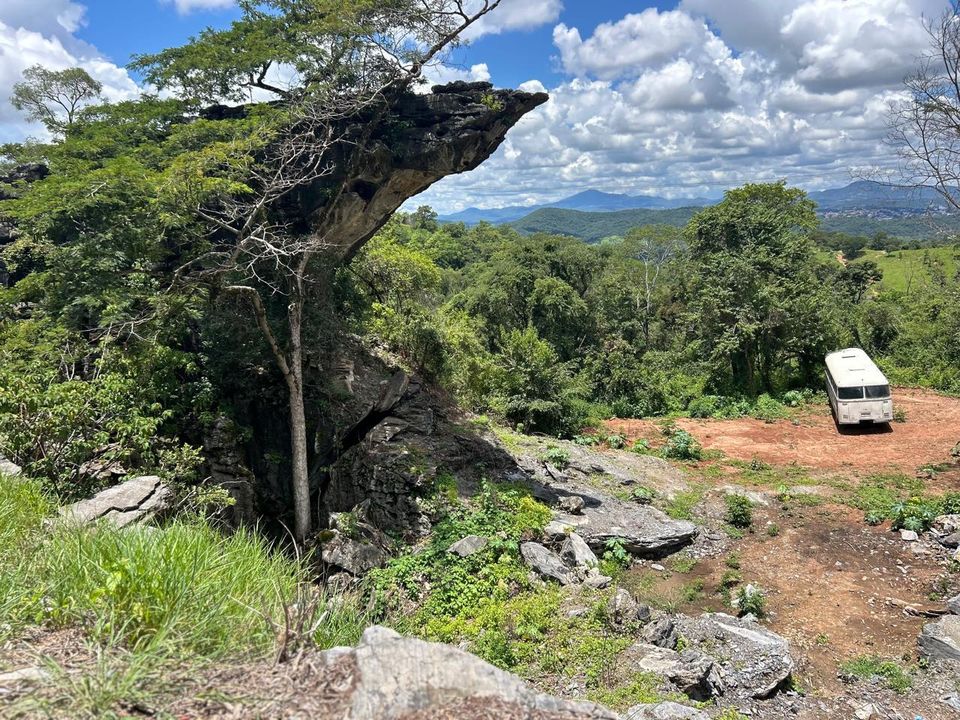 Mirante de pedra com árvore e vista para o vale e as montanhas da serra mineira