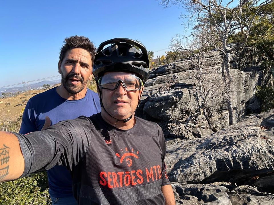 Dois ciclistas de mountain bike em frente a um paredão de rocha