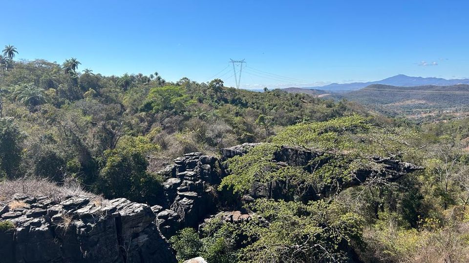 Panorama da serra com formações rochosas, mata nativa e montanhas ao fundo